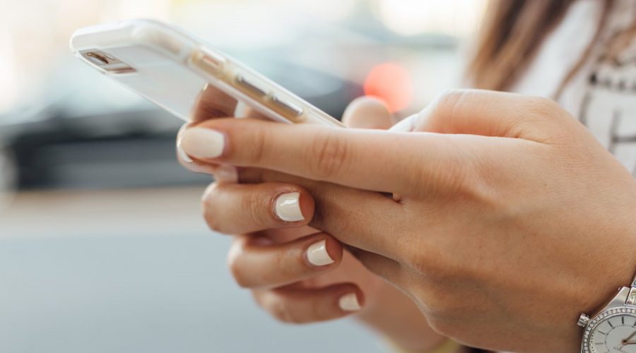 WOMEN HOLDING MOBILE PHONE WITH BOTH HANDS: EXRTREME CLOSE UP